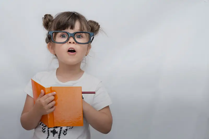 small girl reading a book|hand indicating quantity|boy standing infront of a wall with colorful scribbling