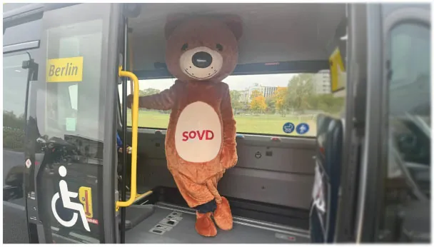 Außenaufnahme des BVG Muva mit gelber Einstiegskante und dem SOVD-Maskottchen im Bus. Die Szene steht für barrierefreie Mobilität in Berlin und unsere PR-Unterstützung durch Events.